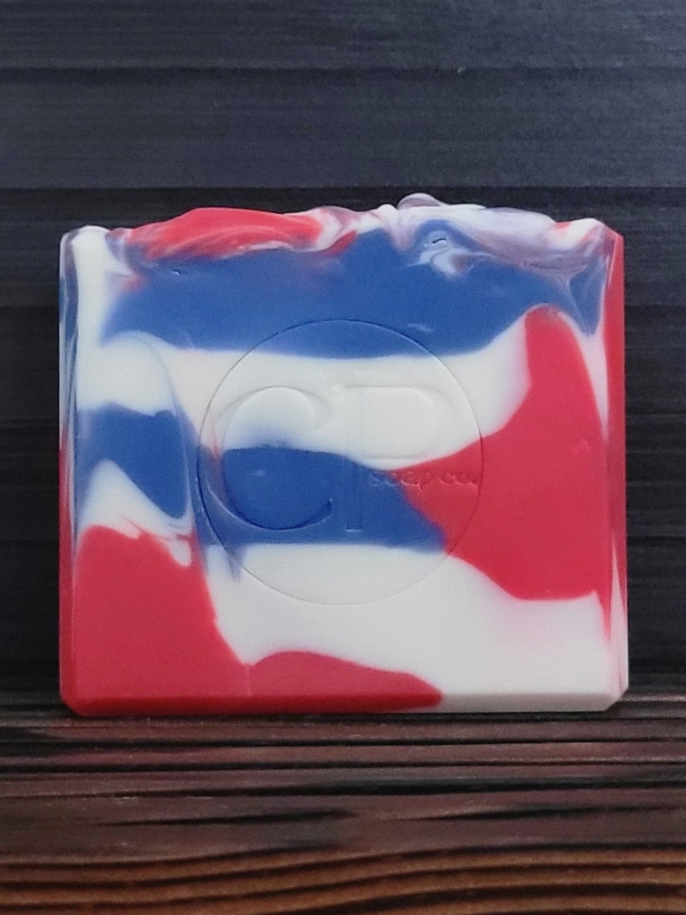 Colorful soap bar with red, white, and blue swirls on a dark background