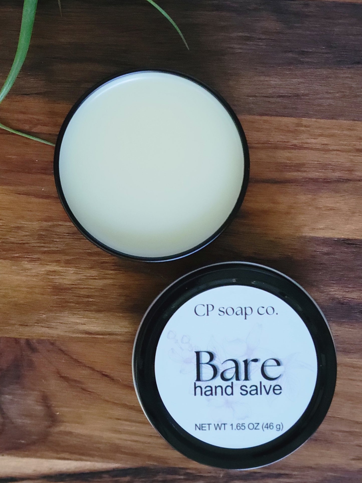 CP Soap Co. Bare hand salve in a black container on a wooden surface