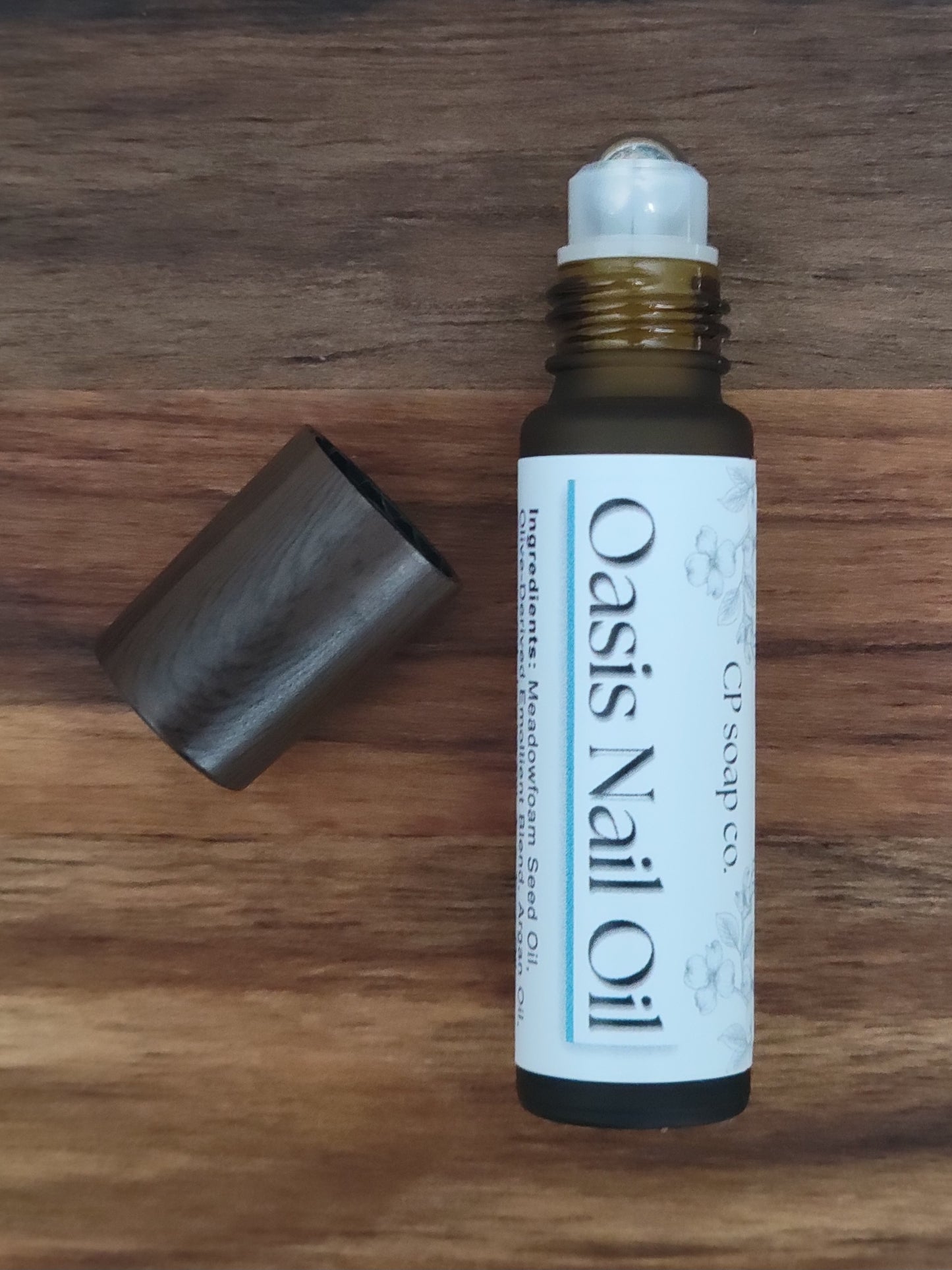 Oasis Nail Oil bottle with roller ball on a wooden surface