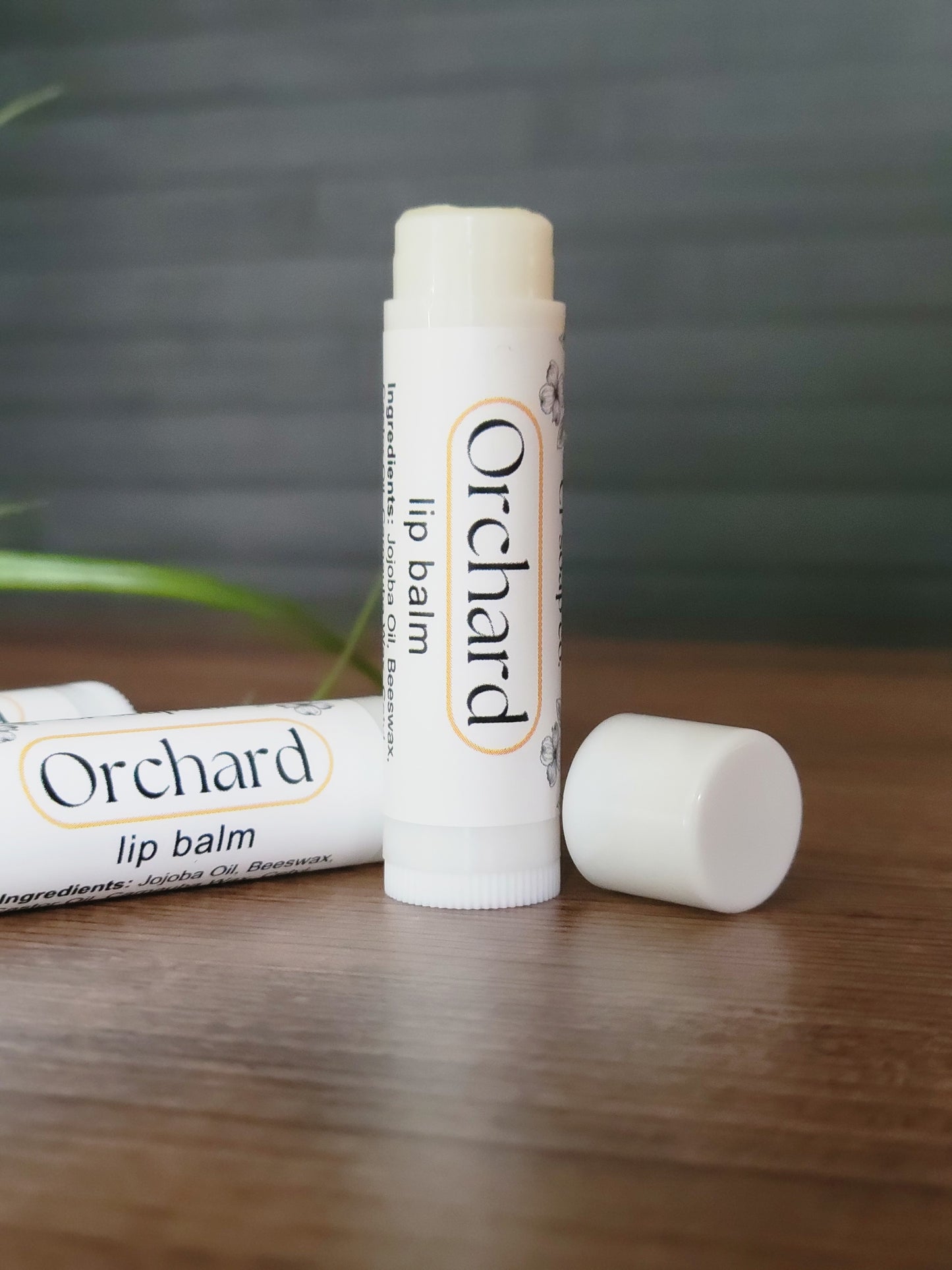Orchard lip balm on a wooden surface with a blurred background