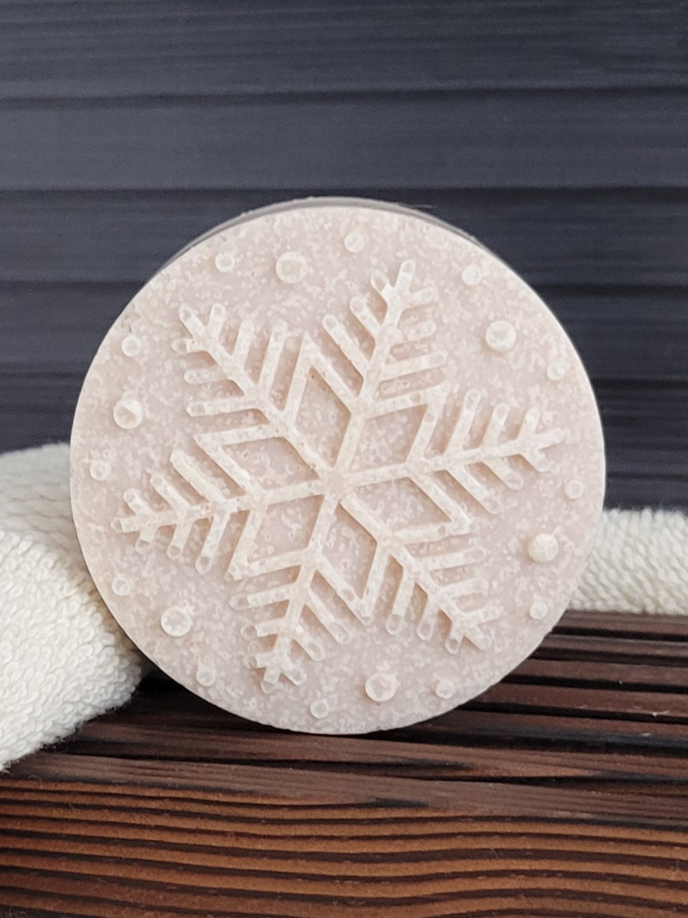 Round beige stone with snowflake design on a wooden surface