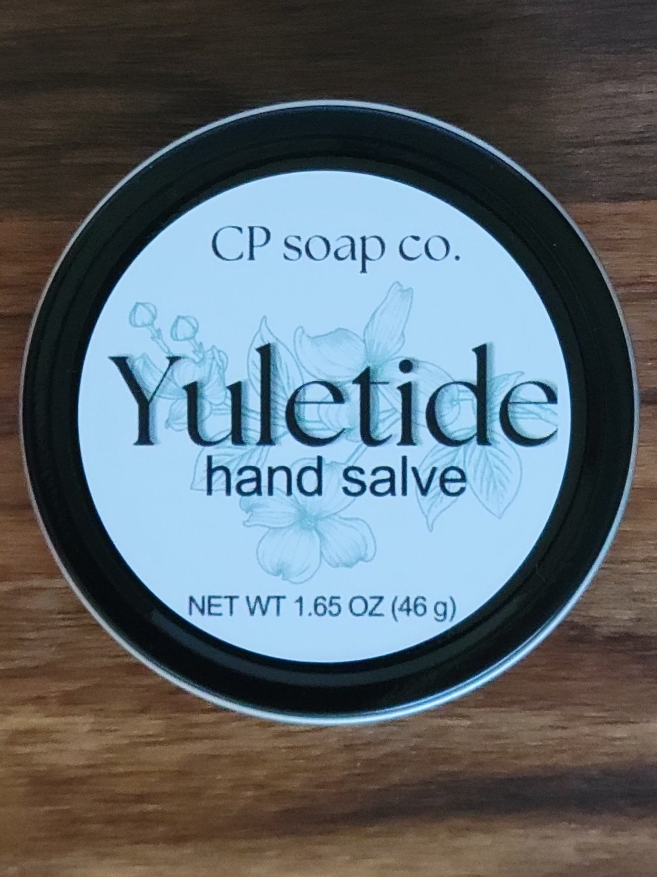 Yuletide hand salve container from CP soap co. on a wooden surface