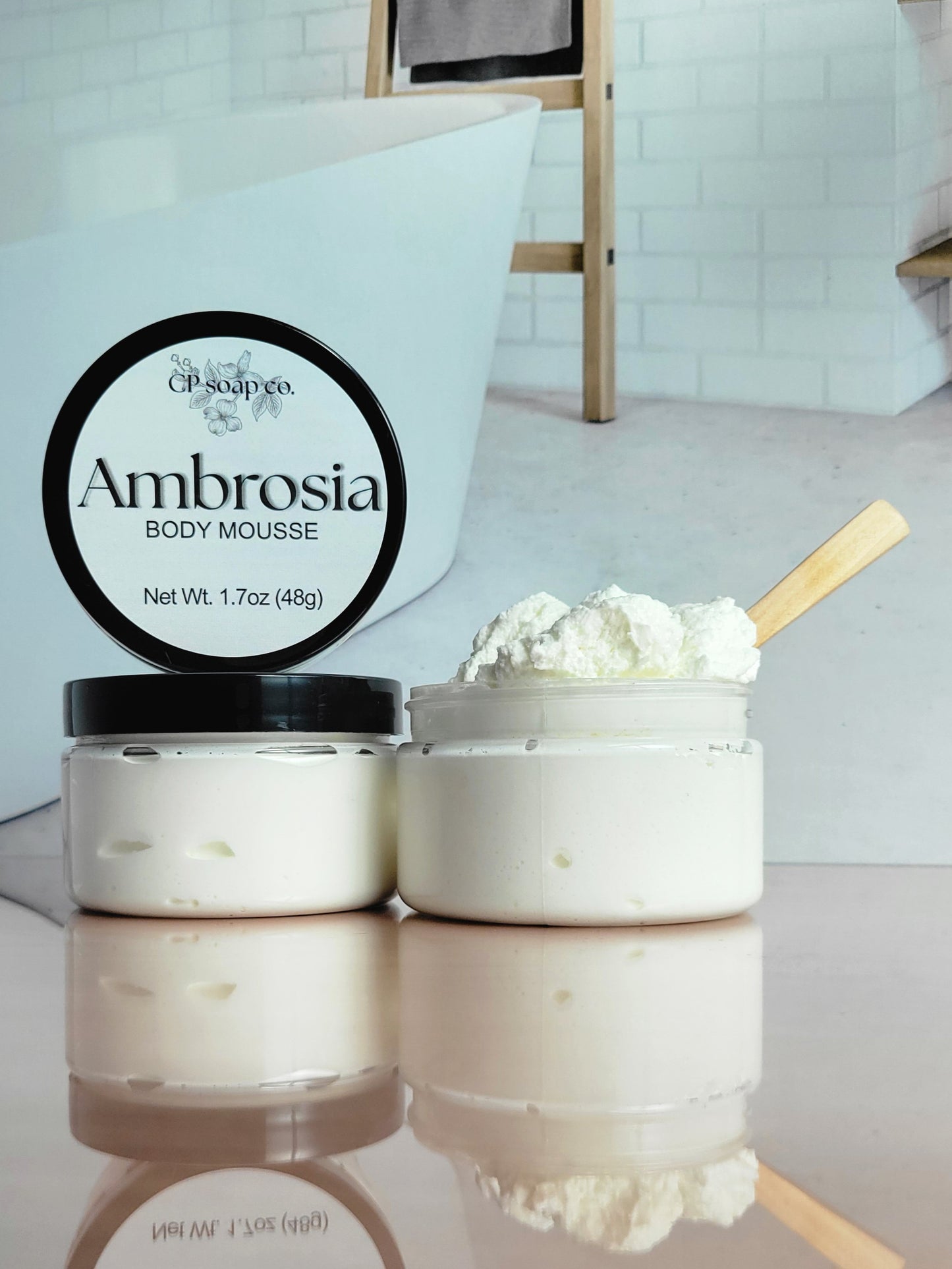 CP Soap Co. Ambrosia Body Mousse container with mousse on a reflective surface.