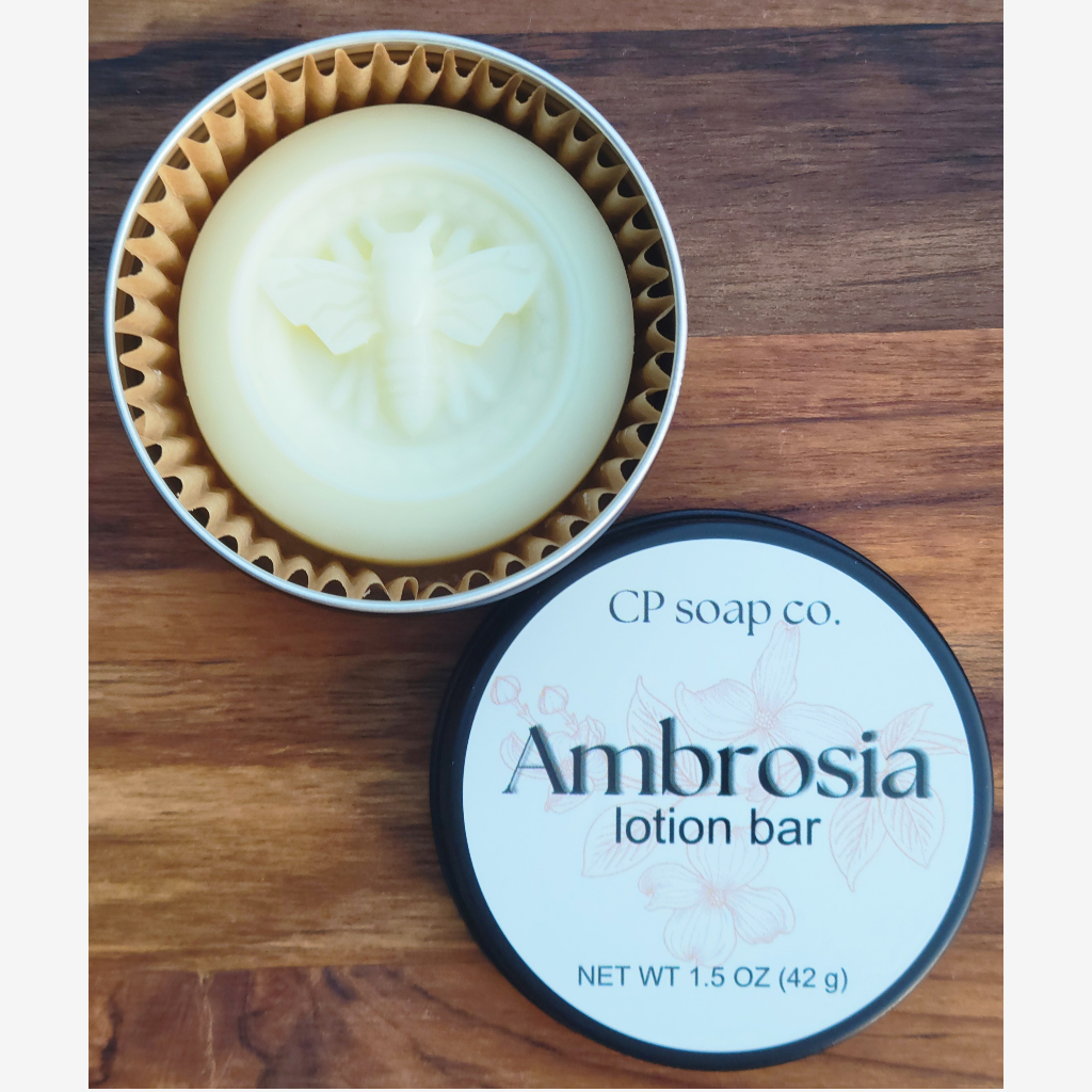 Lotion bar in a tin with 'Ambrosia' label on a wooden surface