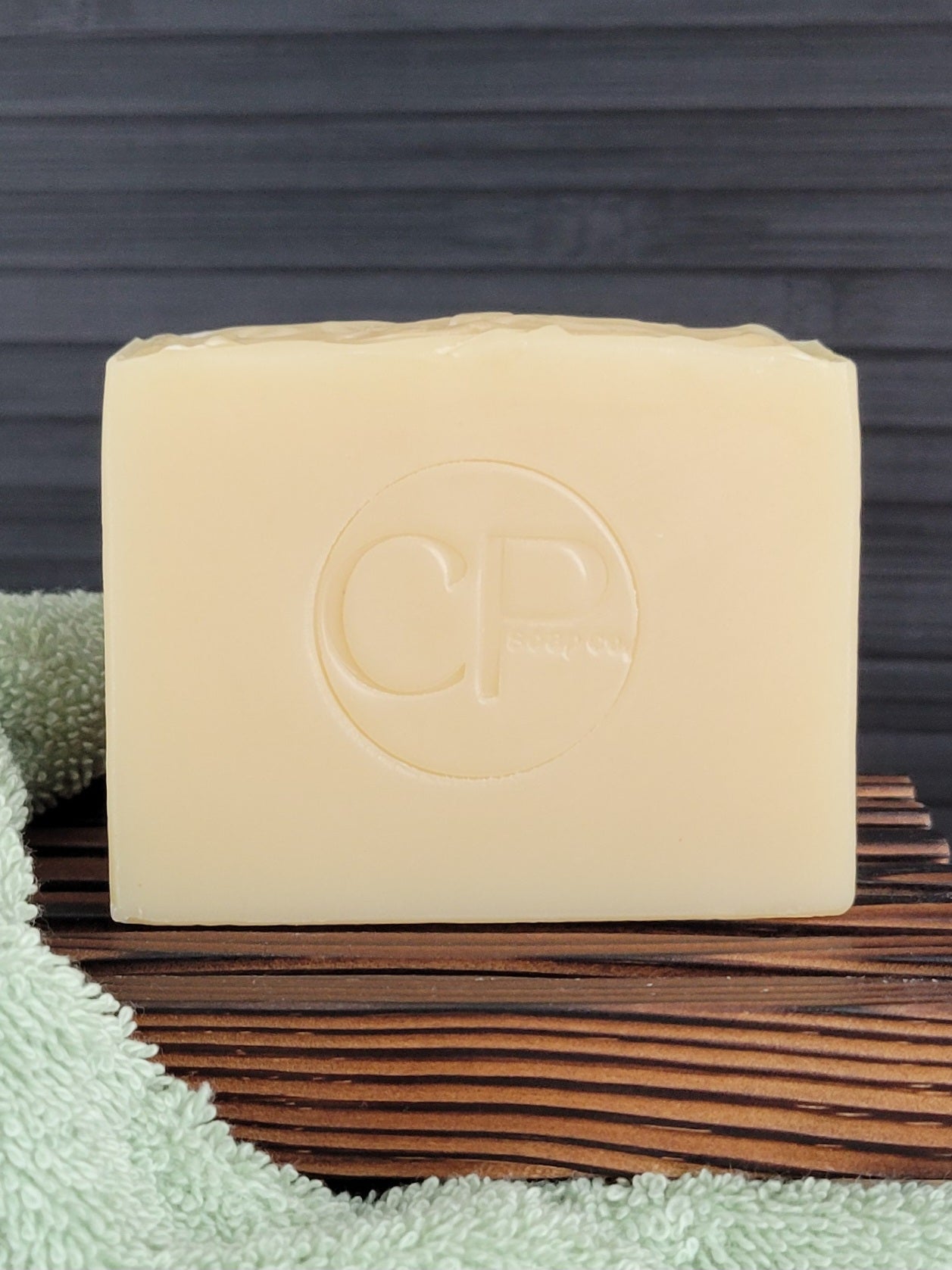 Bar of soap with a brand logo on a wooden surface and towel