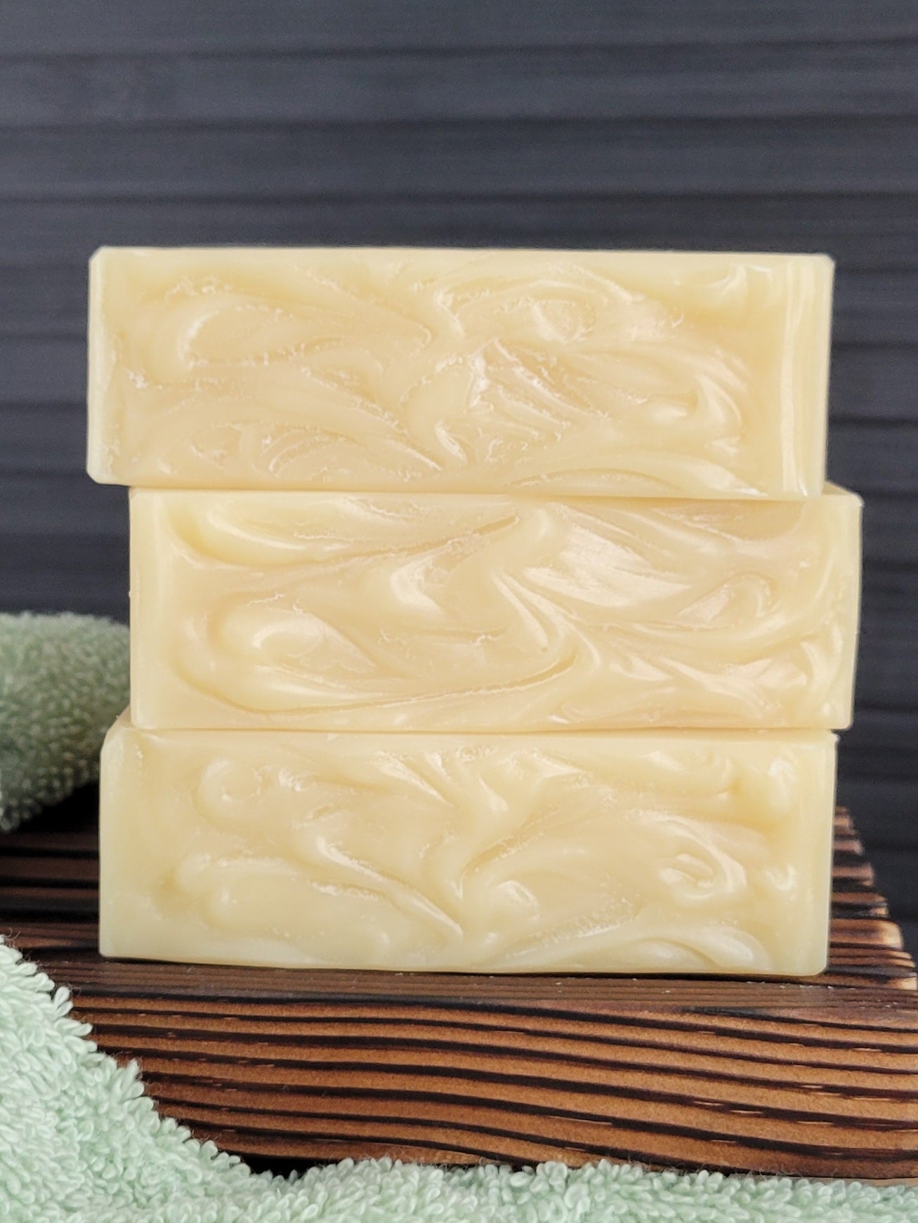 Three stacked bars of soap with a wavy pattern on a wooden surface.
