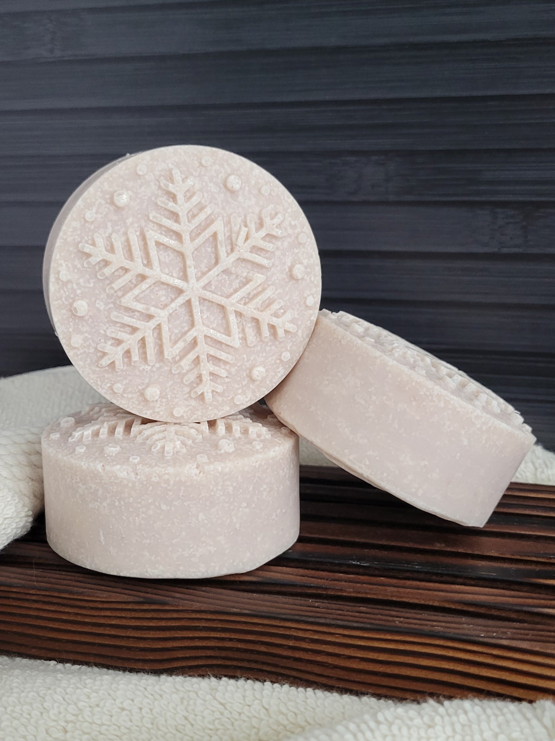 Three soap bars with snowflake design on a wooden surface