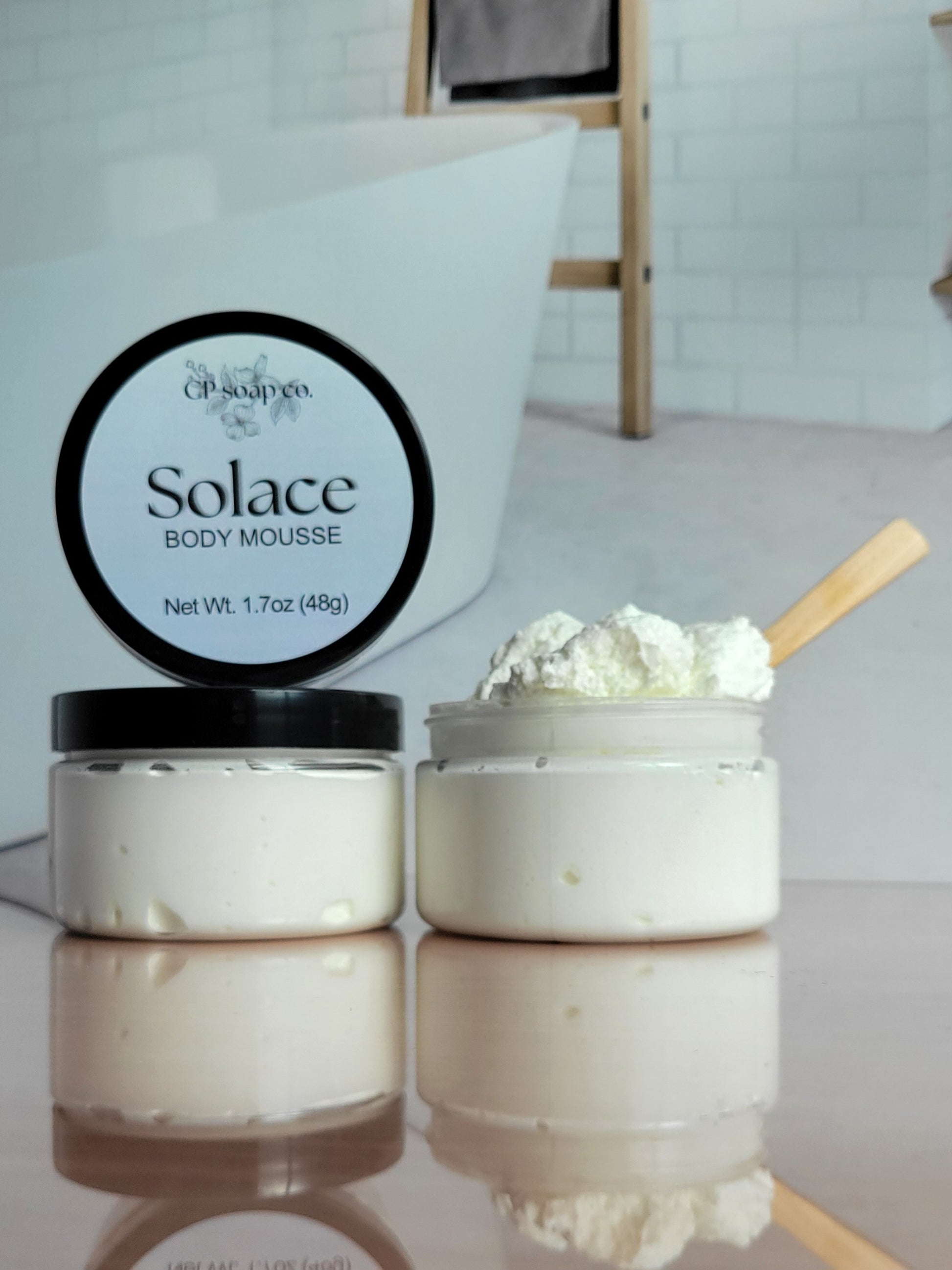 Solace body mousse jar with a spoonful of product on a reflective surface.