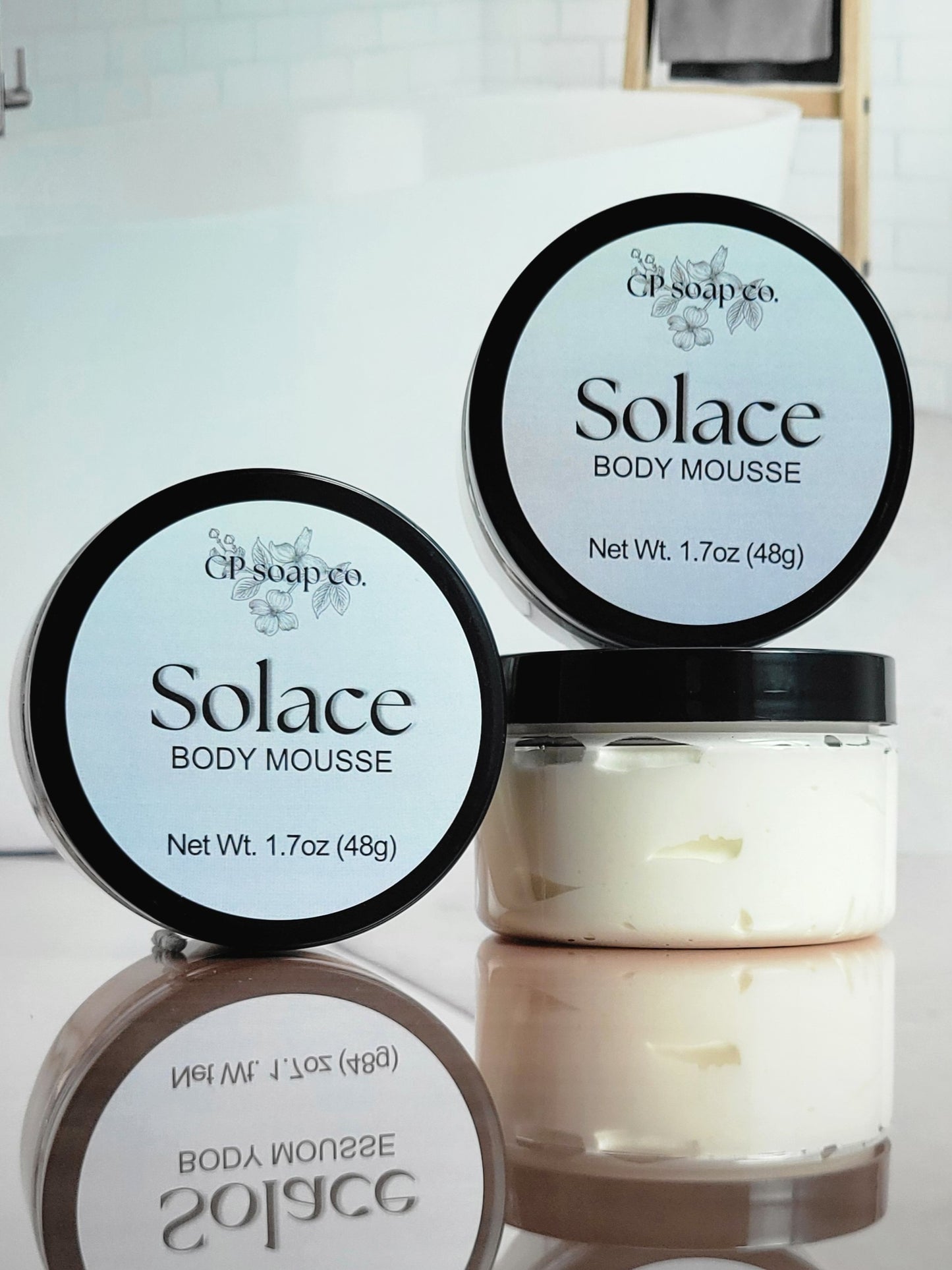Two containers of Solace Body Mousse with visible branding on a reflective surface.