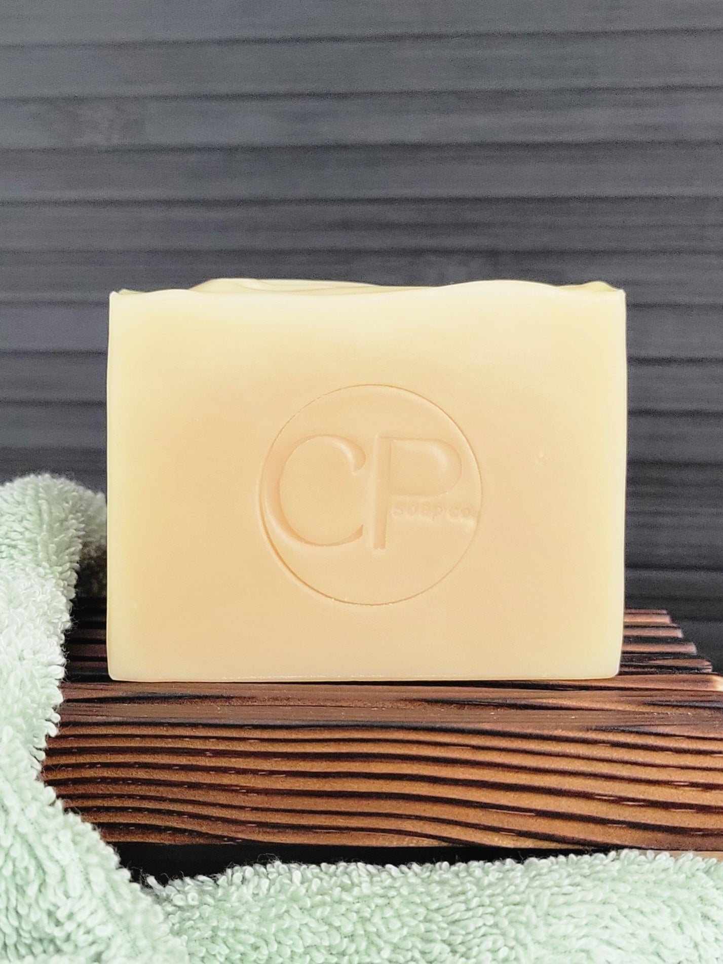 Bar of soap with a logo on a wooden block against a gray background