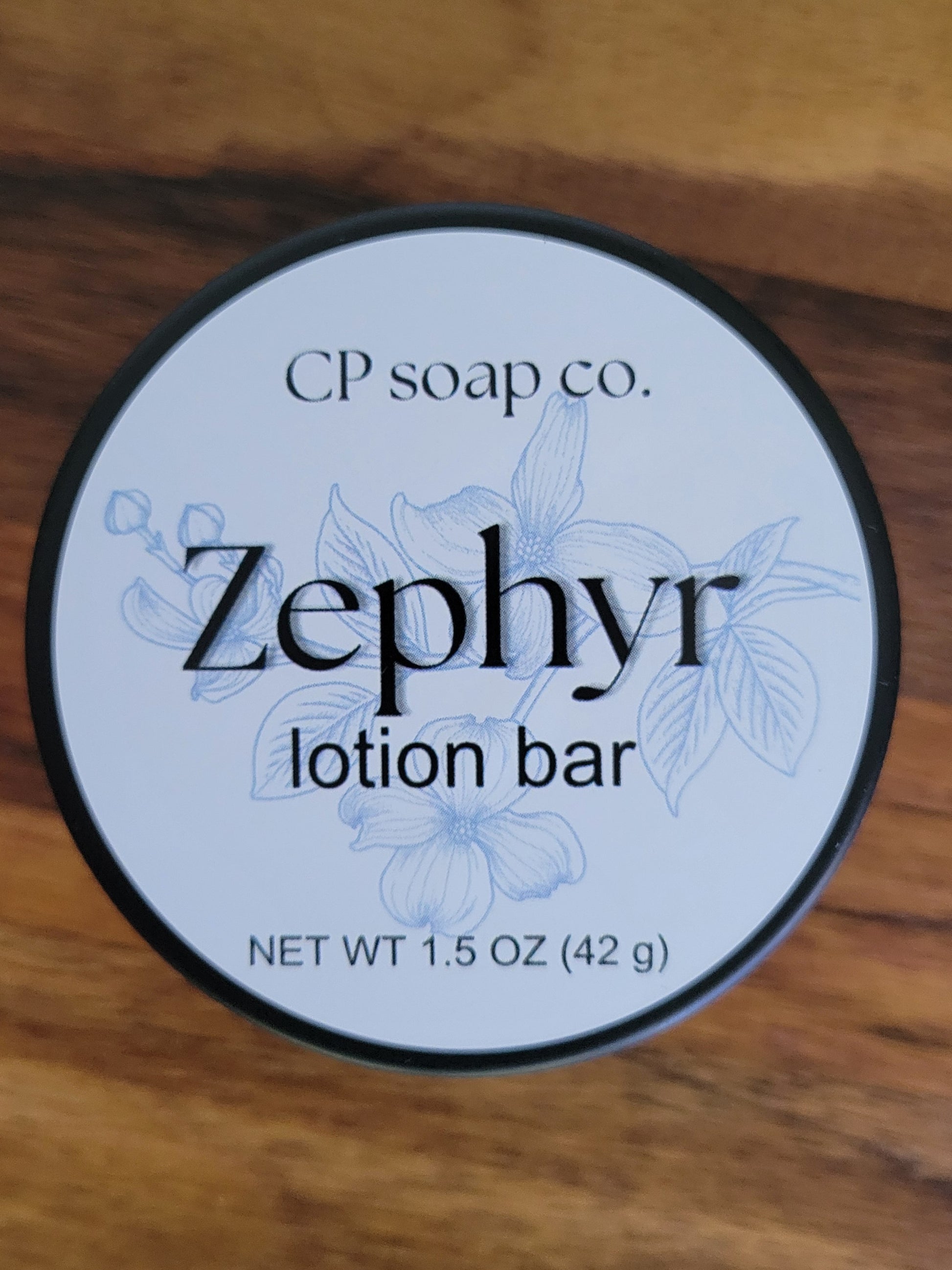 Lotion bar container labeled 'Zephyr' from CP soap co. on a wooden surface