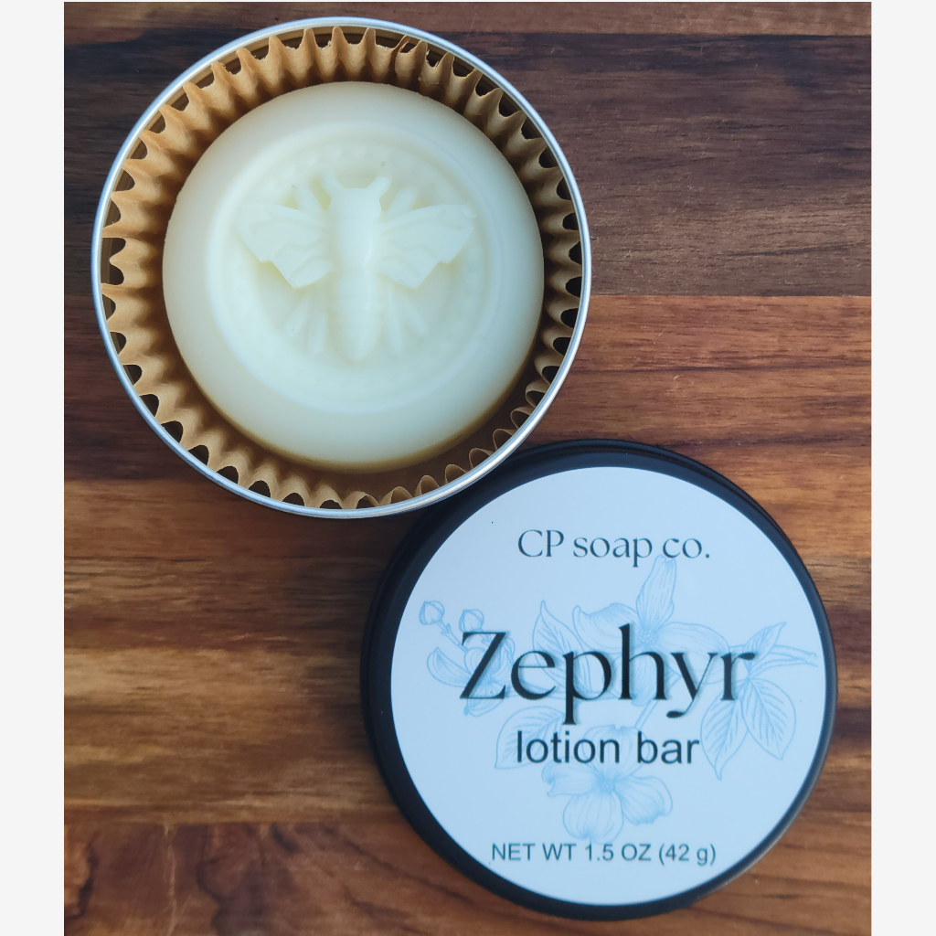 Lotion bar in a tin with its packaging on a wooden surface, branded as CP Soap Co. Zephyr.